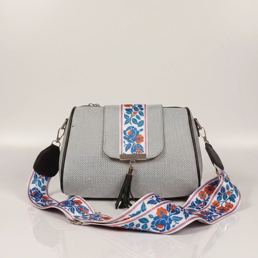 Close up of leather tassel and magnetic closure on a printed jacquard sling bag