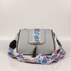 Close up of leather tassel and magnetic closure on a printed jacquard sling bag