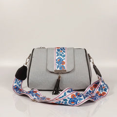 Close up of leather tassel and magnetic closure on a printed jacquard sling bag