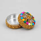 Open gold-toned kumkum box showing its silver-coloured interior and colourful rose-decorated lid
