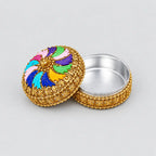 Open gold-toned kumkum box showing its silver-coloured interior and multicolour swirl lid