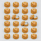 24 gold-toned Jaipuri lac kumkum boxes arranged in rows, with some lids open to show the interiors