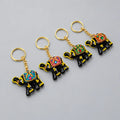 Four black lac elephant keychains with colourful decorated saddles, yellow accents and gold-tone rings
