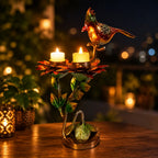 Bird and red lotus candle holder with two lit candles on a wooden table against a warm, softly lit background