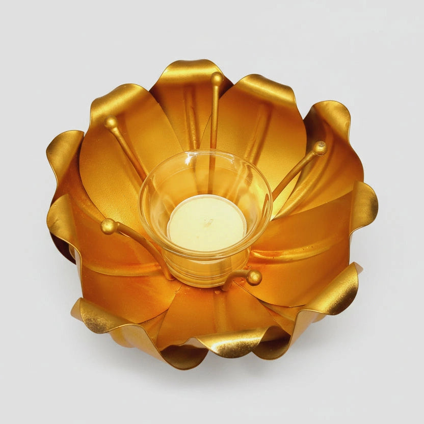 Golden lotus candle holder lit up with a votive candle for a romantic dinner setting.