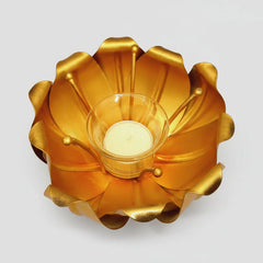Golden lotus candle holder lit up with a votive candle for a romantic dinner setting.