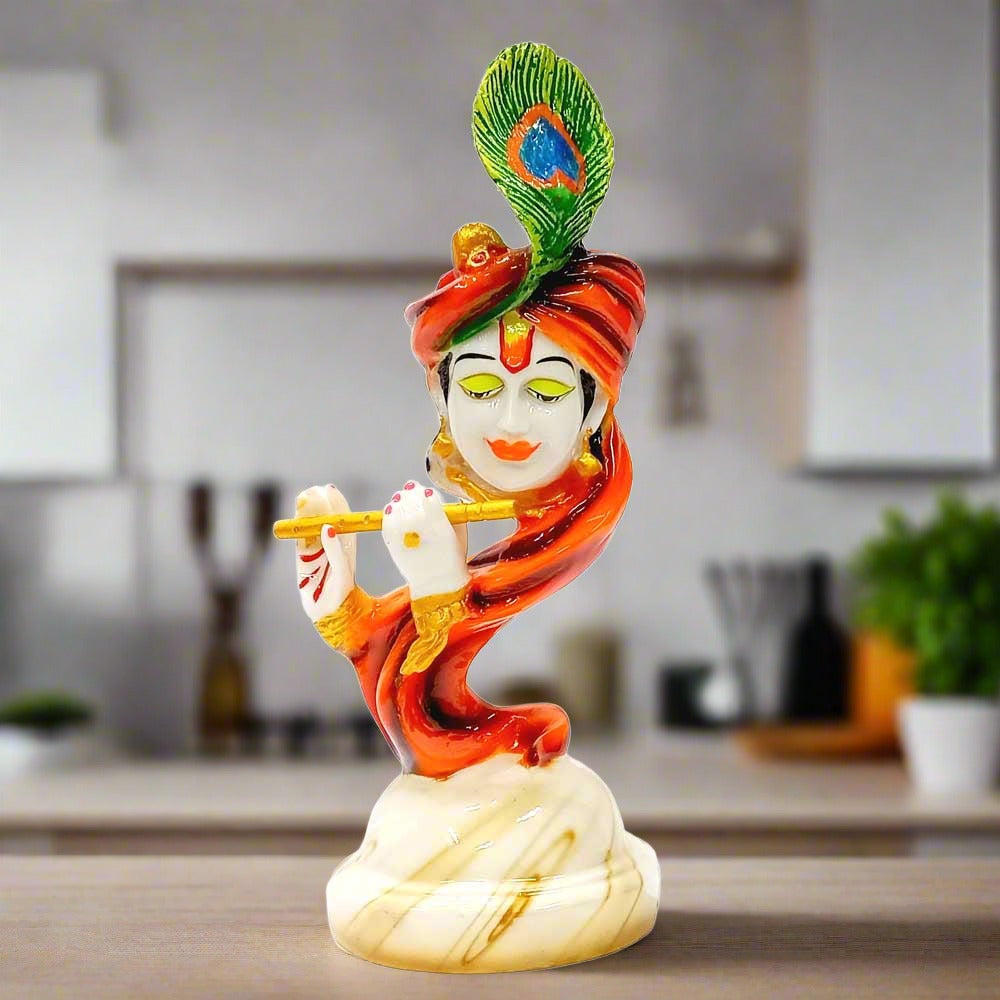 A marble dust Krishna idol playing the flute, decorated with multi-colored accents.