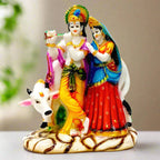 A marble dust Radha Krishna idol standing in front of a cow.