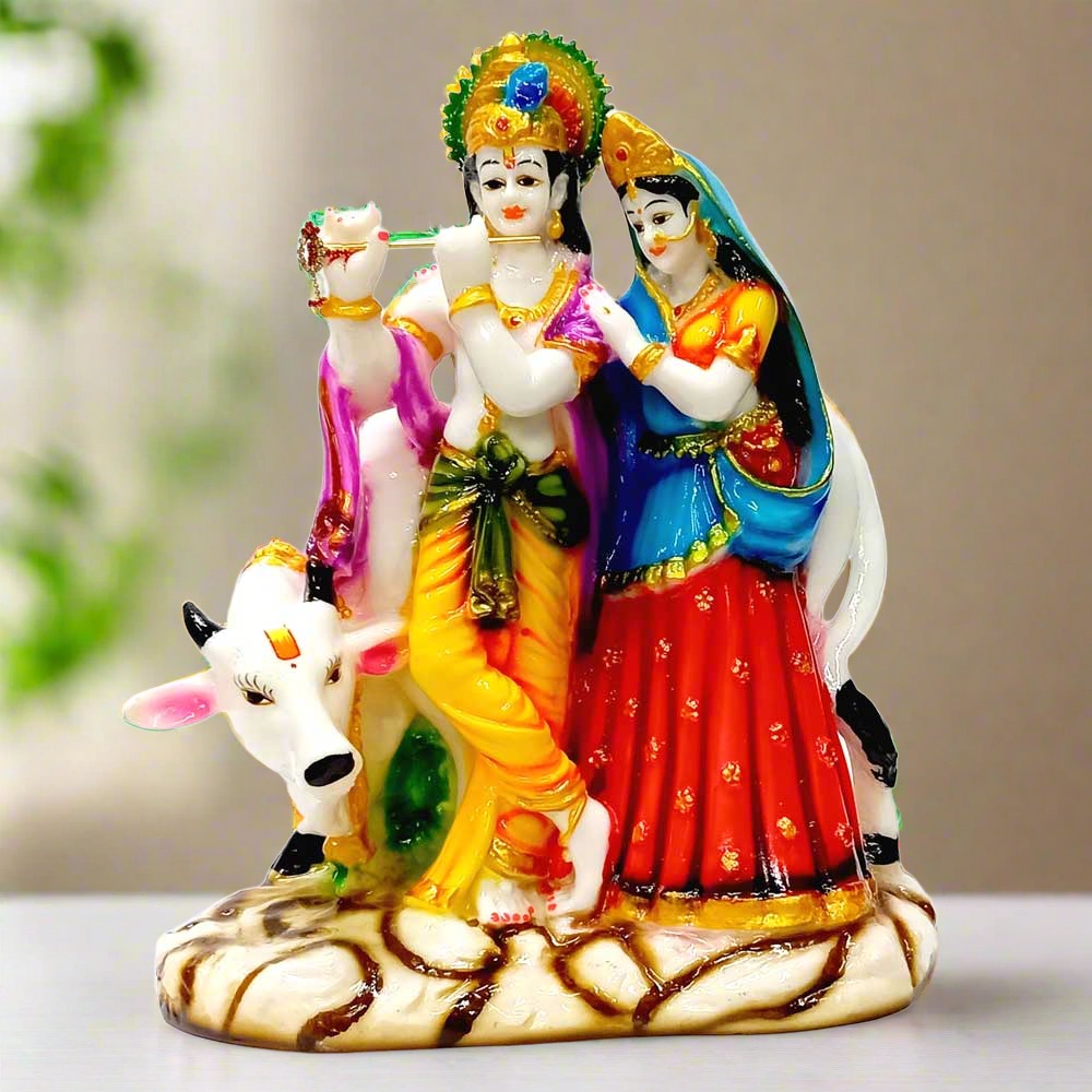 A marble dust Radha Krishna idol standing in front of a cow.