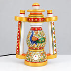 Front view of a marble lantern lamp with a blue and green peacock, floral artwork, red borders and gold trim
