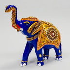 Meenakari elephant statue with a raised trunk and golden saddle decorated with multicolor stones, shown against a light grey background