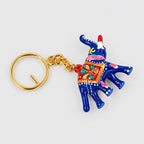 Blue and red Meenakari elephant keychain lying flat with white dotted detailing and a gold-tone ring on the left