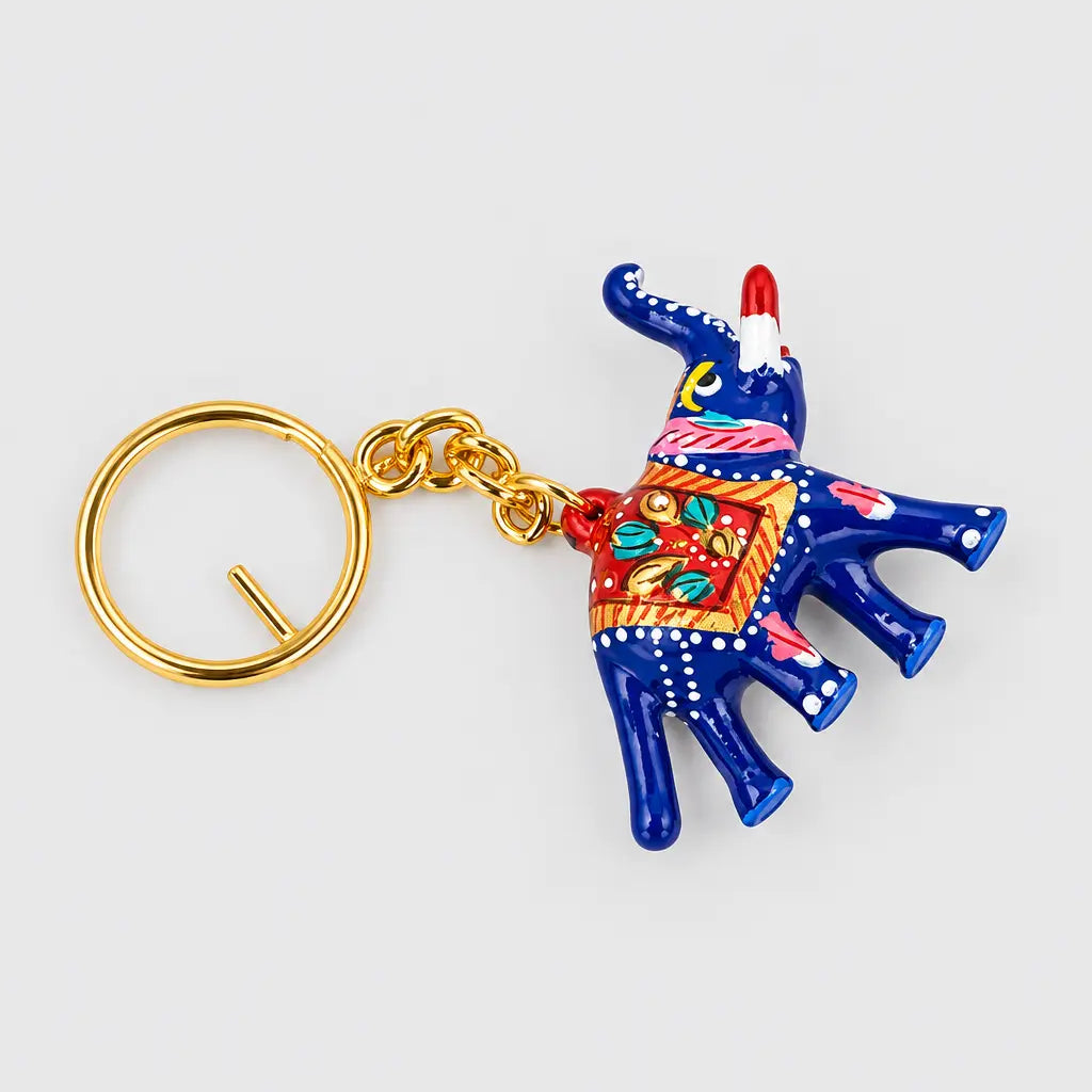 Blue and red Meenakari elephant keychain lying flat with white dotted detailing and a gold-tone ring on the left