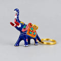 Front angled view of a blue Meenakari elephant keychain showing its raised trunk, pink ears and red patterned saddle