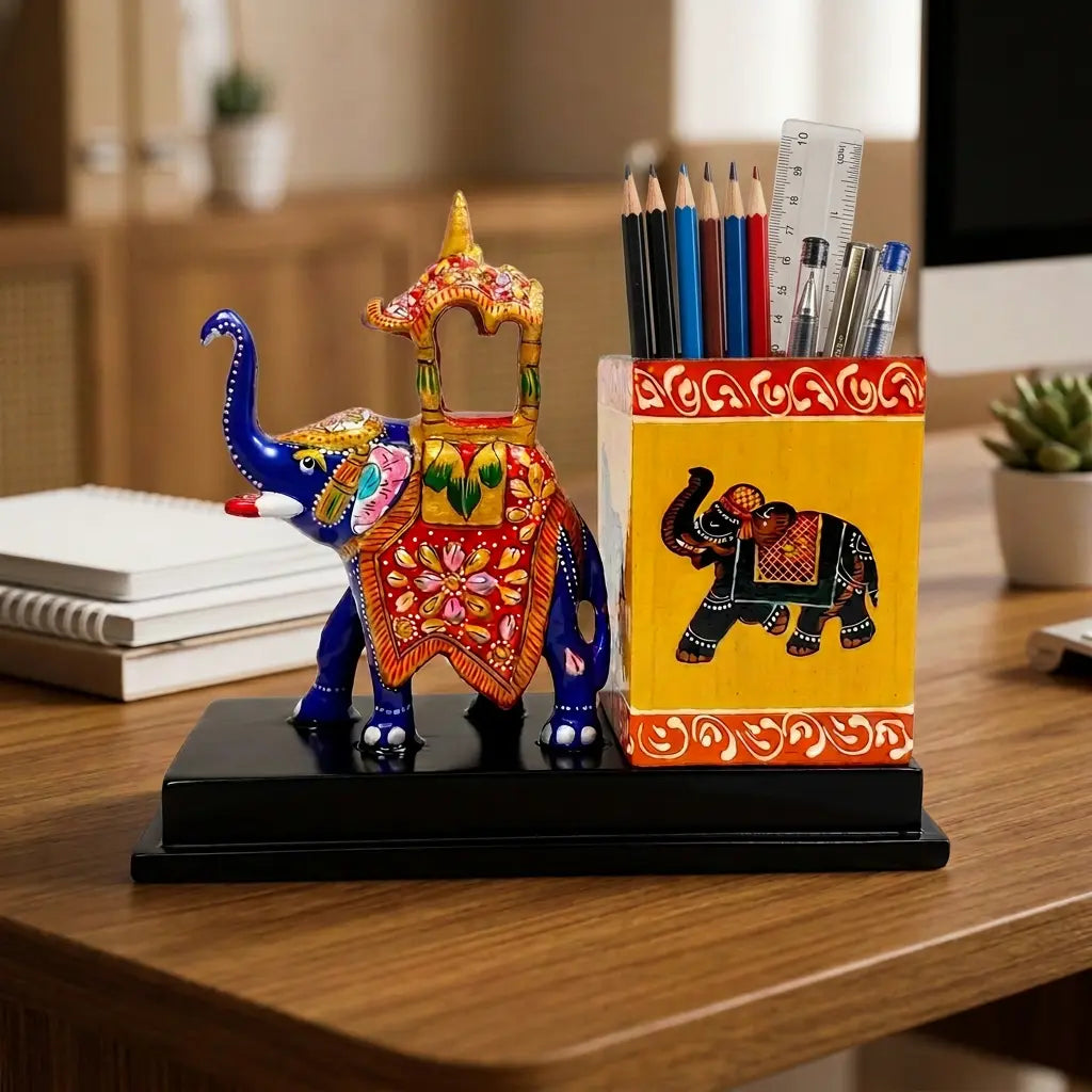 Blue Meenakari elephant beside a yellow pen stand holding pencils, pens and a ruler on an office desk