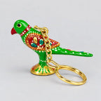 Side view of a green Meenakari parrot keychain with a decorated red wing and gold-tone chain and ring resting in front