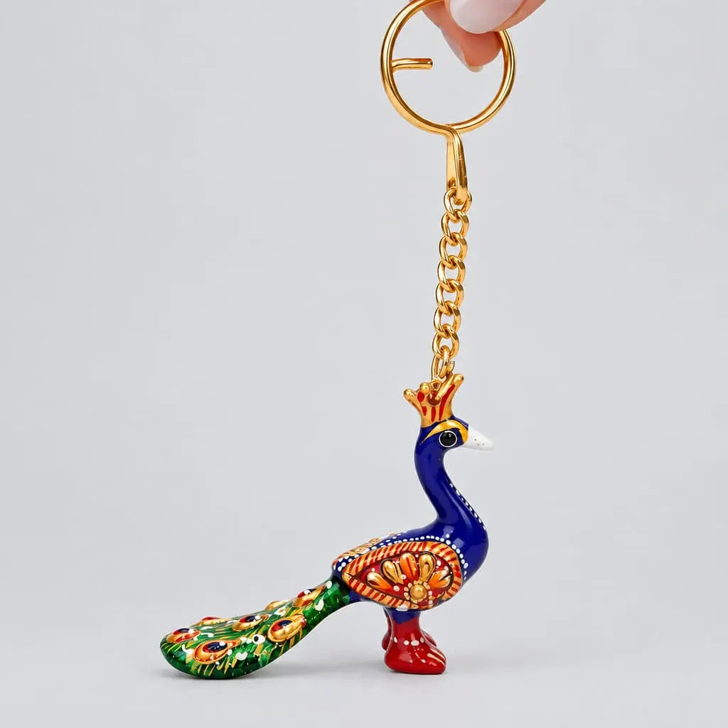 Meenakari peacock keychain hanging from a gold-tone ring, with a blue neck, green tail and floral detailing