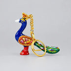Standing Meenakari peacock keychain with a blue neck, floral wing, green tail and gold-tone ring in front
