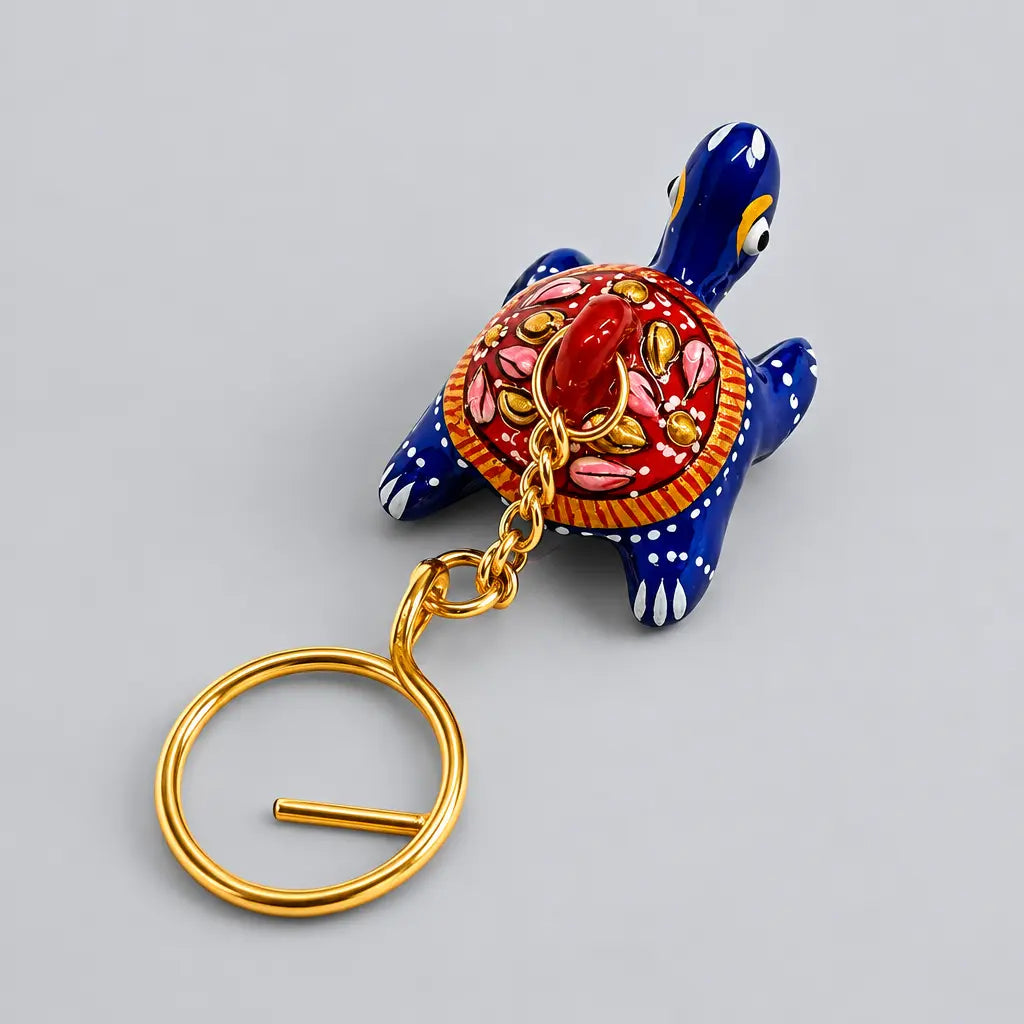Blue Meenakari tortoise keychain with a red floral shell and gold-tone keyring, shown from above