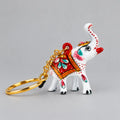 Meenakari white elephant keychain with a raised trunk, red floral saddle and gold-toned chain, facing right.