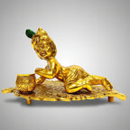 Golden metal Krishna idol on leaf, a perfect spiritual gift for baby shower and housewarming ceremonies.