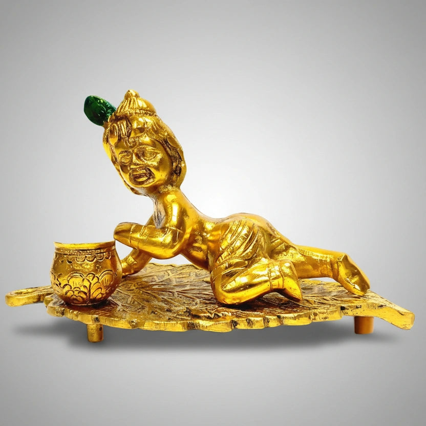 Golden metal Krishna idol on leaf, a perfect spiritual gift for baby shower and housewarming ceremonies.