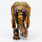 Front view of Mughal painted wooden elephant idol with a floral vine along the black trunk, white tusks and colourful head decoration