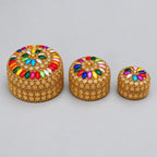 Three round lac boxes arranged from large to small, with multicolour petal-shaped stones on the lids and golden detailing around the sides.