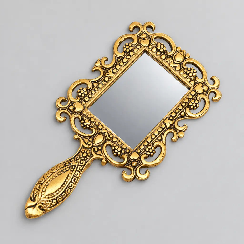 Metal hand mirror with an oxidized golden finish, rectangular glass and an ornate floral scrollwork frame and handle.