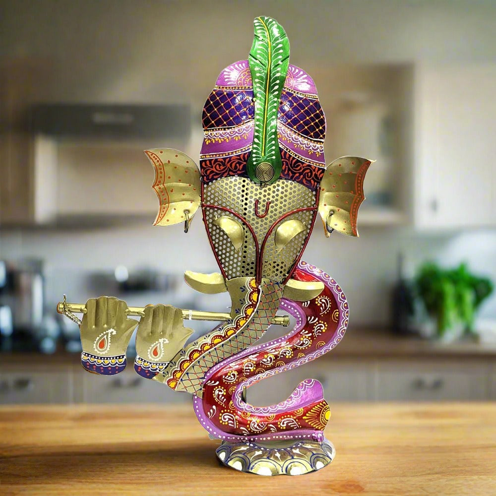A painted metal Ganesh figurine with a functional candle holder on the back.