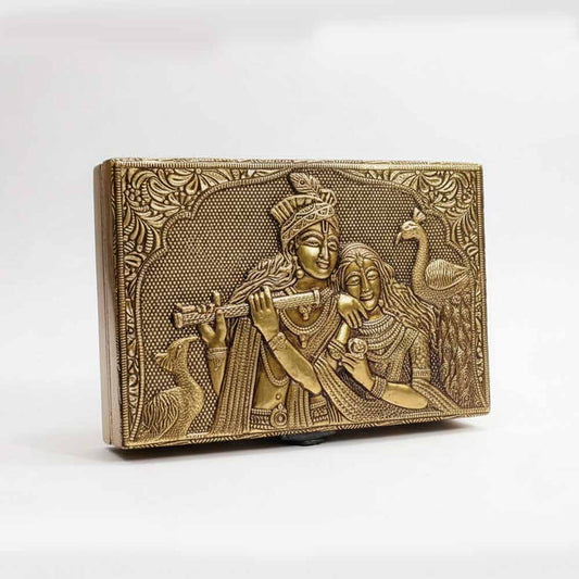 Closeup of intricate golden embossed Radha Krishna design and floral border on box lid.