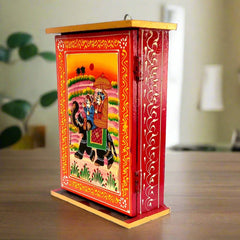 A wooden key organizer with 6 hooks, featuring a beautiful Raja Savari (Ambari Elephant) hand painting.
