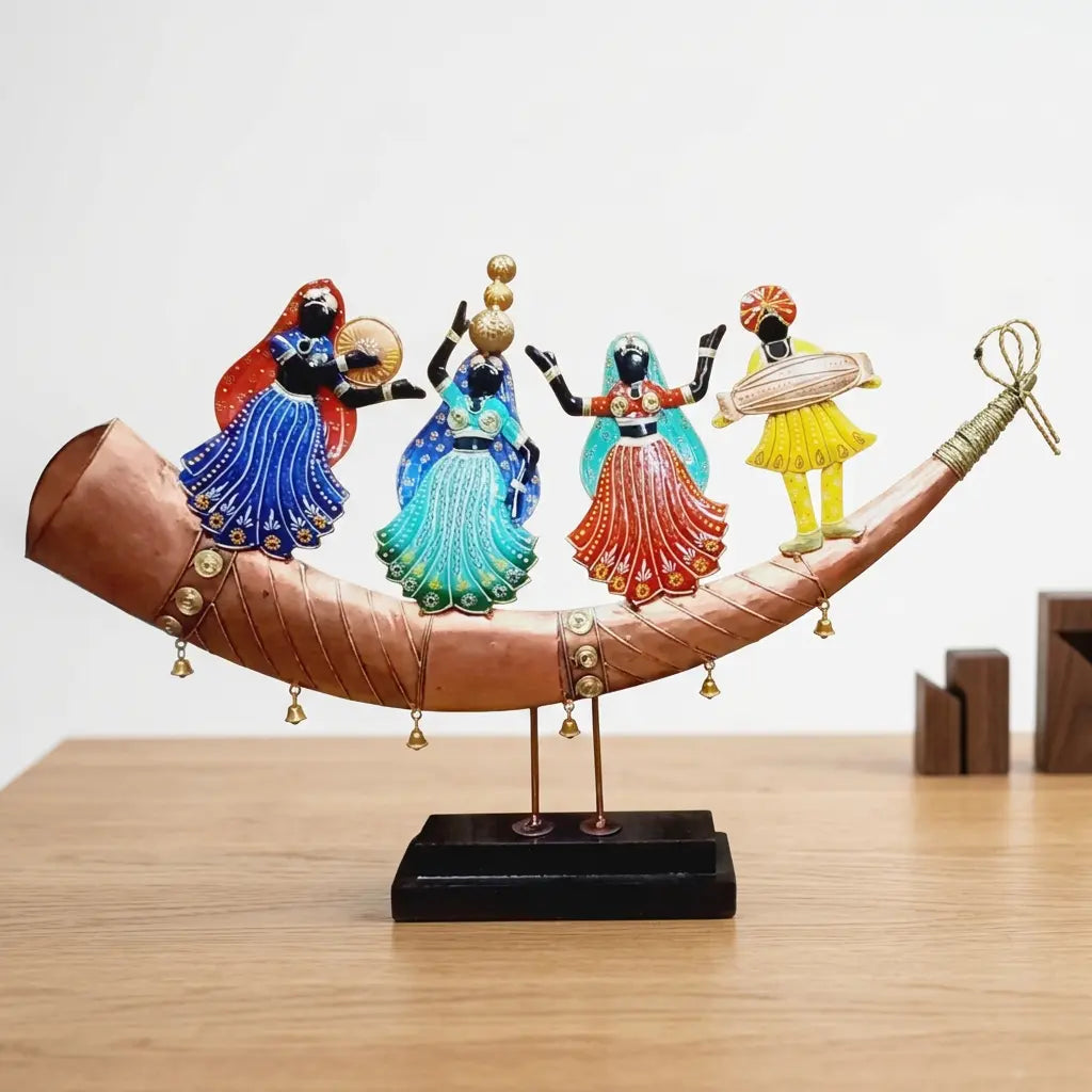 Front view of hand painted Rajasthani dancers and a dhol player on a shehnai shaped metal base with bells and a black wooden platform
