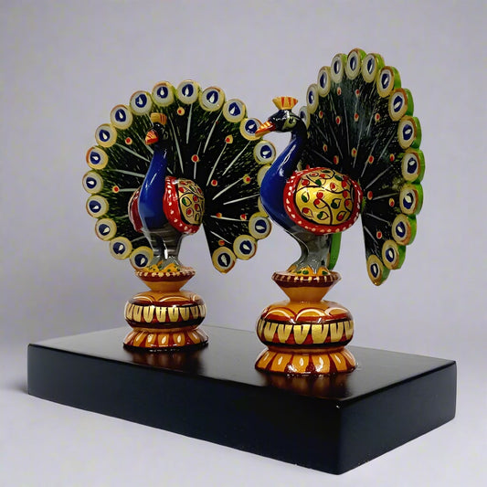 Two wooden dancing peacocks on a platform featuring vibrant hand-painted Rajasthani art.