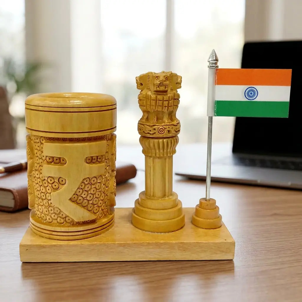 Round wooden pen holder with carved rupee symbol, Ashok Stambh and Indian flag on an office desk beside a laptop