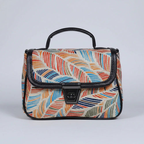 Front view of a small floral print ethnic crossbody bag with button closure.