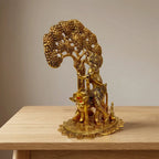 Standing Krishna murti holding a flute beside a cow under a tree