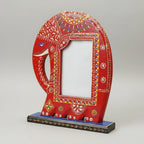 Close-up of a handcrafted red wooden elephant frame featuring intricate colorful paintwork and a sturdy tabletop base, perfect for bohemian home decor.