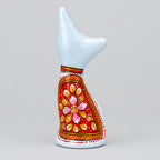 Back view of a white Meenakari metal cat with pink and gold flowers on a red panel