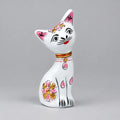 White Meenakari metal cat with a tilted head, pink ears and pink and gold floral detailing