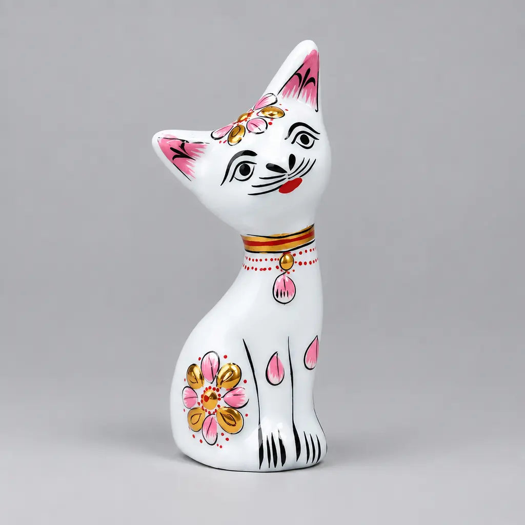 White Meenakari metal cat with a tilted head, pink ears and pink and gold floral detailing
