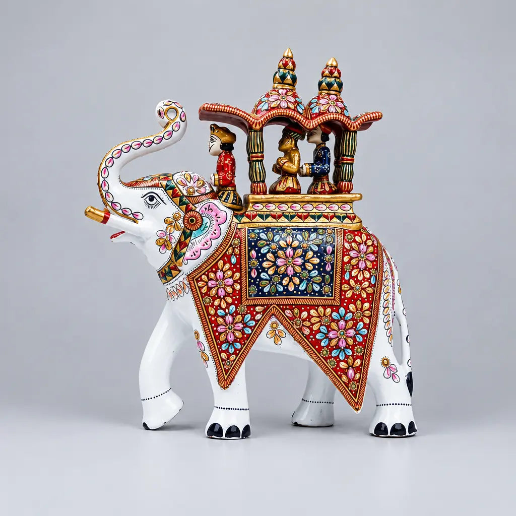 Left-side profile of a white Ambabari elephant with a raised trunk, red and navy floral saddle panels and three riders beneath a decorated canopy.