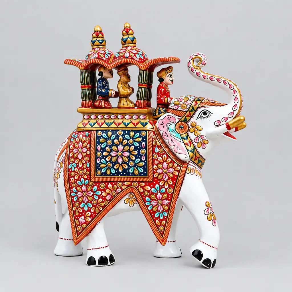 Side view of a white Meenakari Ambabari elephant with multicolour floral decoration, a raised trunk and three rider figures beneath a twin-domed canopy.