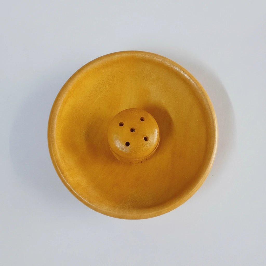 A hand-carved wooden incense holder for sticks and cones.