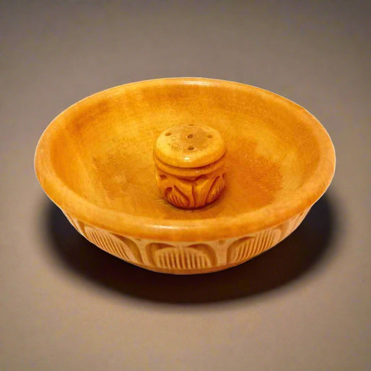 A hand-carved wooden incense holder for sticks and cones.