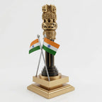 Wooden Ashoka Pillar showing carved golden lions, wheel and animal motifs above two crossed Indian flags