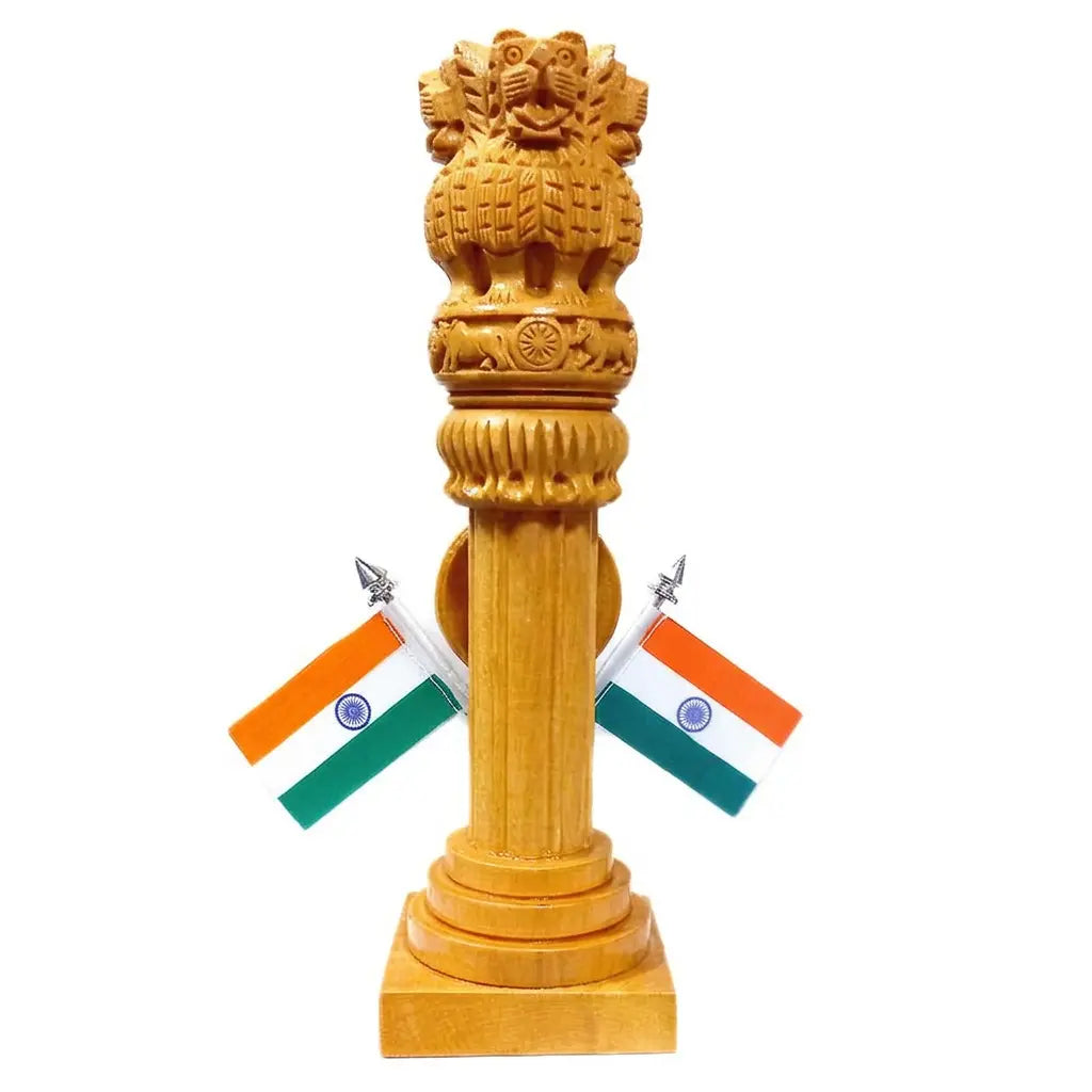 Rear view of a carved wooden Ashoka Pillar on a square base with two Indian flags against a white background