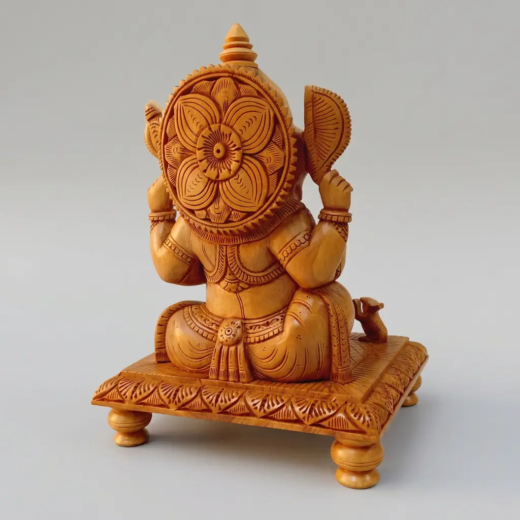 Back view of a wooden Ganesh idol showing the floral carving behind the crown and detailed chowki border
