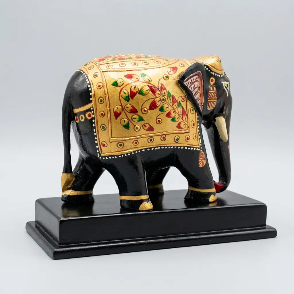 Rear angled view of a wooden elephant memento showing gold decoration with red and green floral patterns