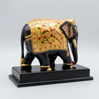 Rear angled view of a wooden elephant memento showing gold decoration with red and green floral patterns